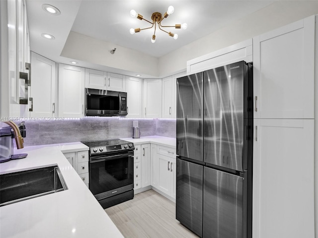 kitchen featuring white cabinets, light hardwood / wood-style floors, electric range oven, and black fridge