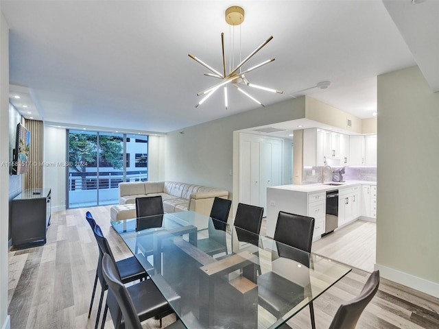 dining space with sink, light hardwood / wood-style floors, expansive windows, and a notable chandelier