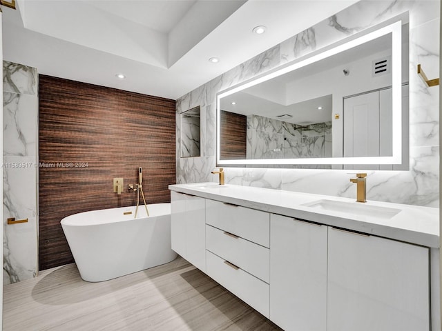 bathroom with a washtub, dual bowl vanity, tile flooring, and tile walls