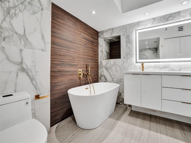 bathroom featuring tile walls, a tub, vanity, and toilet