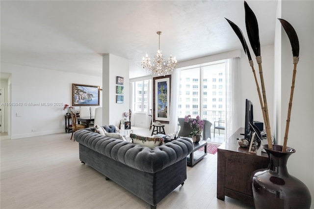 living area featuring light wood-type flooring, a notable chandelier, and baseboards