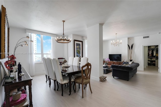 dining area with a notable chandelier, light wood-style floors, and visible vents