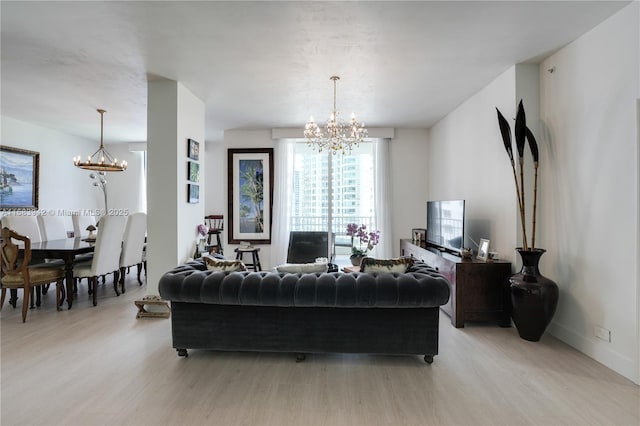 living area with a notable chandelier, baseboards, and light wood finished floors