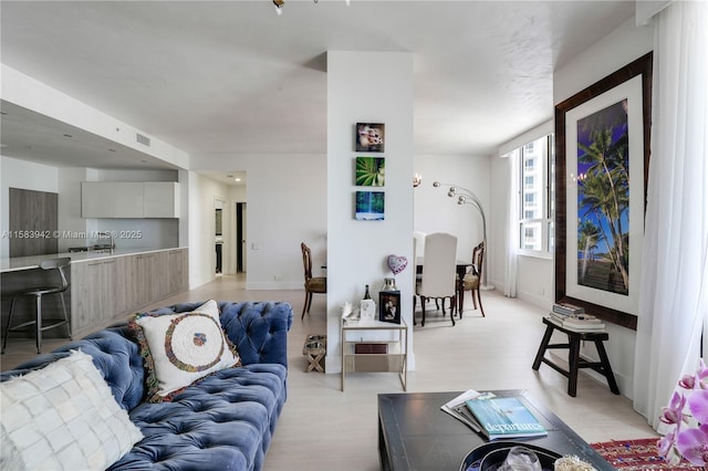 living area featuring light wood-style flooring, baseboards, and visible vents