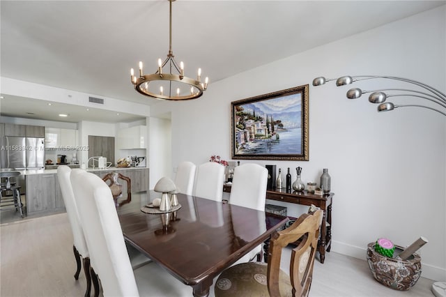 dining area featuring a notable chandelier, visible vents, light wood-style flooring, and baseboards