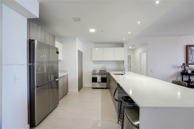 kitchen featuring modern cabinets, a sink, a kitchen breakfast bar, stainless steel appliances, and a peninsula