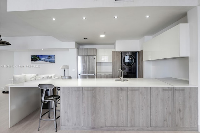 701 Brickell Key Blvd Unit Lph-06, Miami, FL 33131 - kitchen featuring stainless steel refrigerator, modern cabinets, stacked washer / dryer, a peninsula, and light countertops