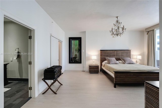 bedroom featuring connected bathroom, baseboards, a chandelier, and light wood finished floors