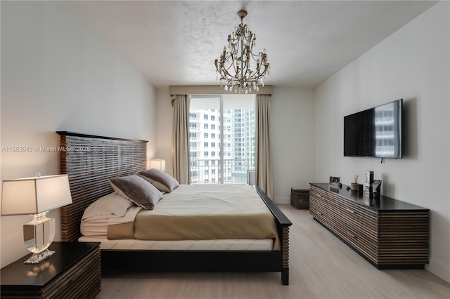 bedroom featuring baseboards, an inviting chandelier, and light wood-style flooring