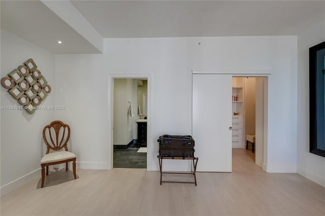 interior space with connected bathroom, baseboards, and light wood-style floors