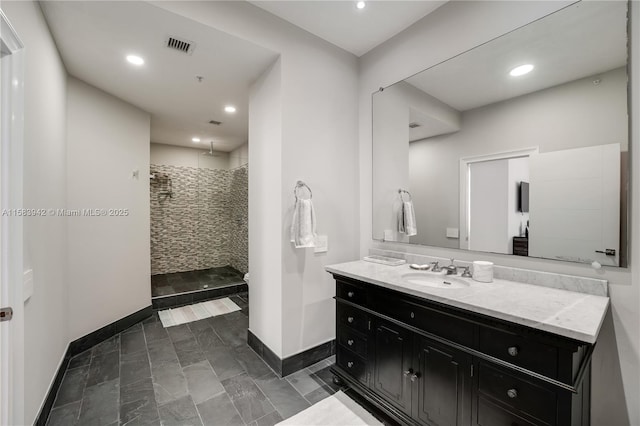 full bath with vanity, visible vents, baseboards, recessed lighting, and a tile shower