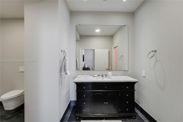 bathroom with toilet, vanity, and baseboards