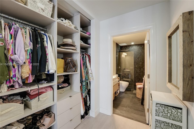 walk in closet with light wood finished floors