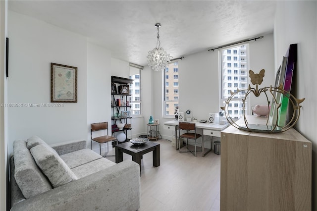 living room with light wood finished floors, a notable chandelier, and baseboards