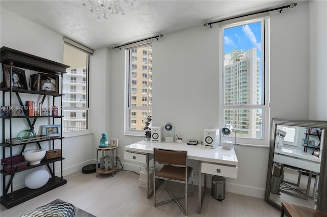 office space featuring baseboards, a healthy amount of sunlight, and light wood-style flooring