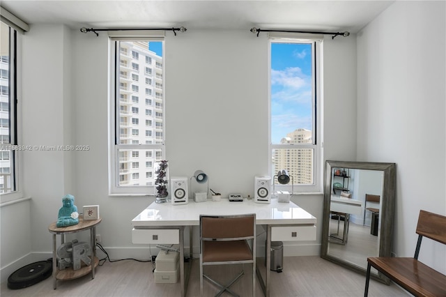 home office featuring a city view, plenty of natural light, baseboards, and light wood finished floors