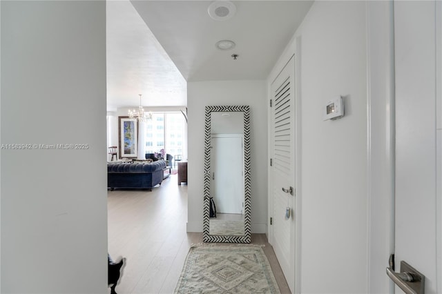 hall featuring a notable chandelier and light wood-type flooring