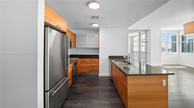 kitchen featuring kitchen peninsula, appliances with stainless steel finishes, dark hardwood / wood-style floors, and sink