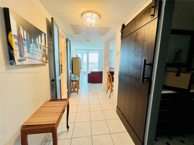 corridor featuring tile flooring and a barn door