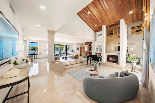 living room featuring wood ceiling, a large fireplace, ornate columns, and high vaulted ceiling