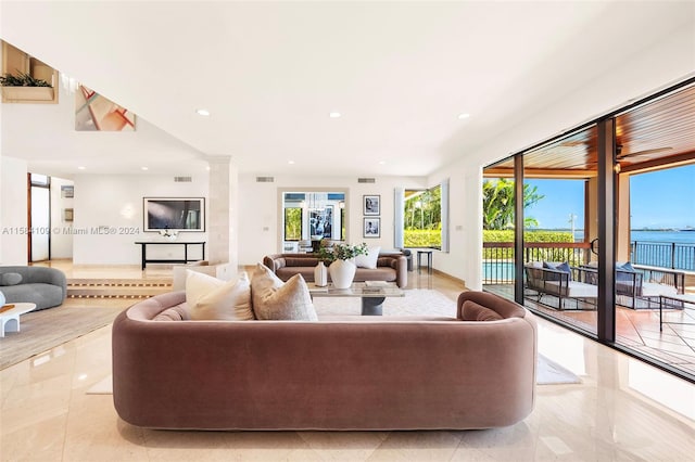 living room with a water view, a wealth of natural light, and decorative columns