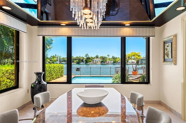 tiled dining space featuring a water view, a wealth of natural light, and an inviting chandelier