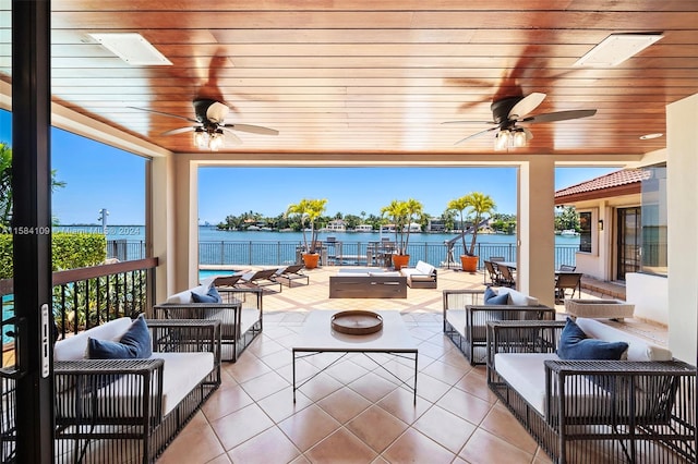 view of patio with a water view, an outdoor living space with a fire pit, and ceiling fan