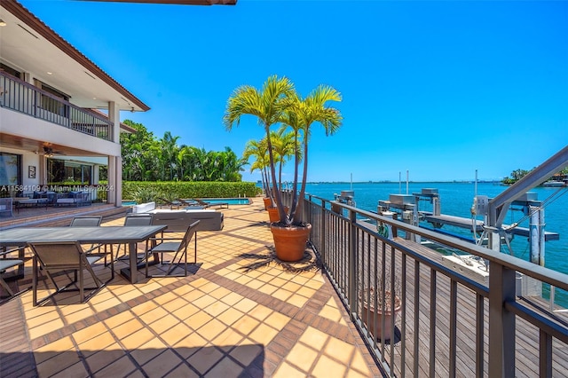 view of patio / terrace featuring a water view, a dock, and a balcony