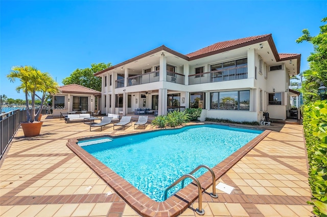 rear view of house featuring outdoor lounge area, a patio area, a balcony, and a fenced in pool