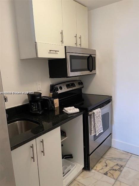 kitchen featuring dark stone countertops, white cabinets, and stainless steel appliances