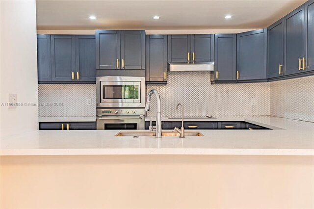 kitchen with light stone counters, appliances with stainless steel finishes, sink, and tasteful backsplash