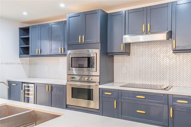 kitchen with stainless steel appliances, blue cabinetry, wine cooler, sink, and tasteful backsplash