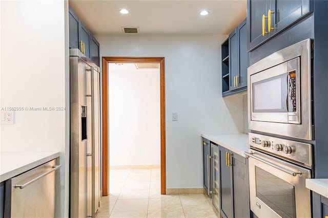 kitchen with appliances with stainless steel finishes, blue cabinetry, and light tile floors