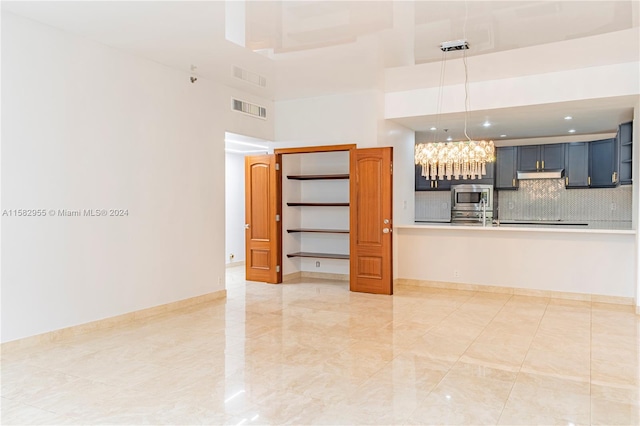 unfurnished living room featuring a high ceiling, light tile flooring, and a notable chandelier