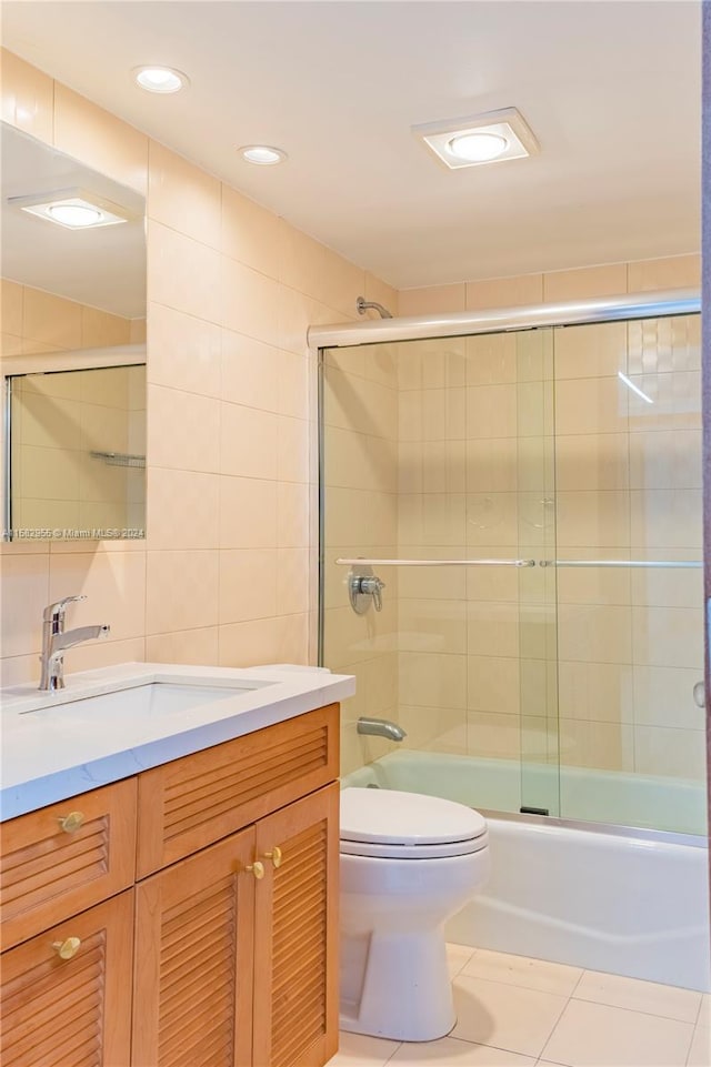 full bathroom featuring shower / bath combination with glass door, tile walls, toilet, tile flooring, and vanity