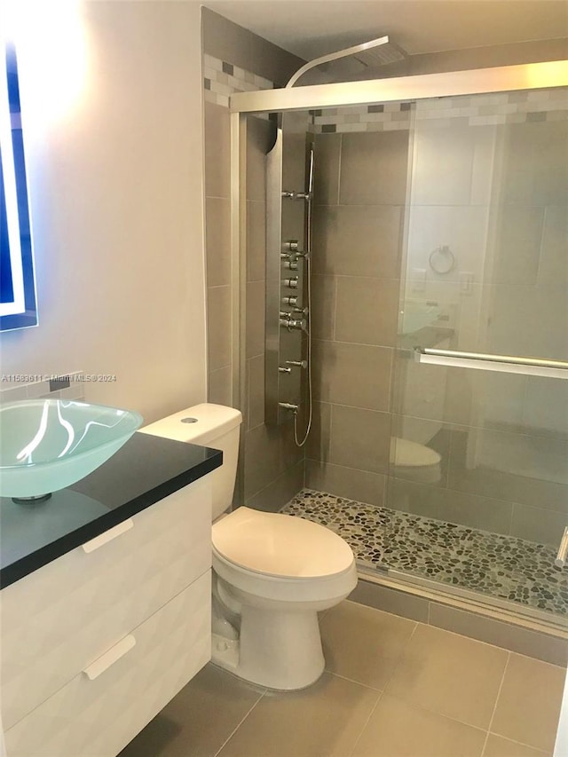 bathroom featuring tile floors, vanity, toilet, and a shower with shower door