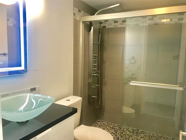 bathroom featuring toilet, a shower with shower door, and large vanity