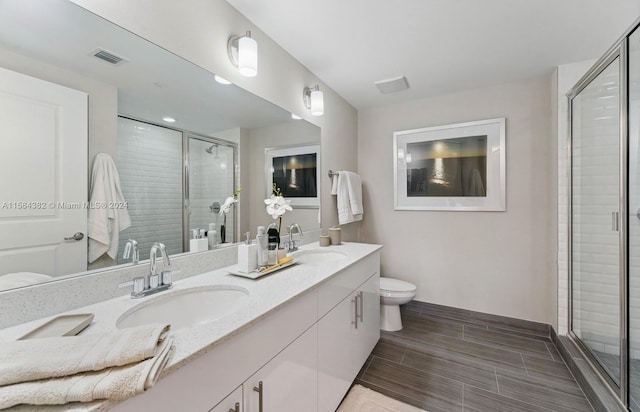 bathroom with toilet, a shower with door, and vanity