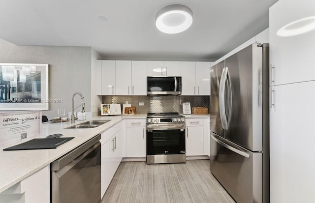 kitchen featuring white cabinets, stainless steel appliances, tasteful backsplash, and sink