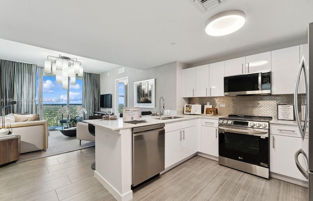 kitchen with appliances with stainless steel finishes, white cabinetry, kitchen peninsula, and sink