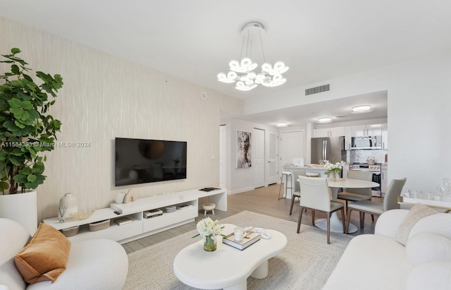 living room with light wood-type flooring and a notable chandelier