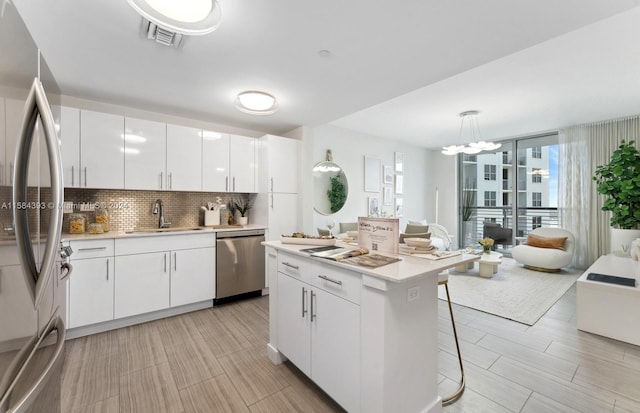 kitchen with sink, hanging light fixtures, appliances with stainless steel finishes, a breakfast bar area, and white cabinets