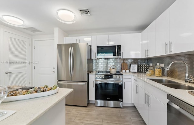 kitchen featuring stainless steel appliances, decorative backsplash, white cabinetry, and sink