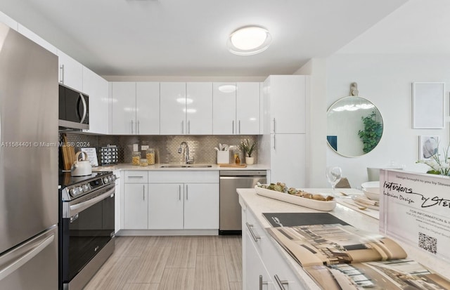 kitchen featuring sink, appliances with stainless steel finishes, white cabinetry, and decorative backsplash