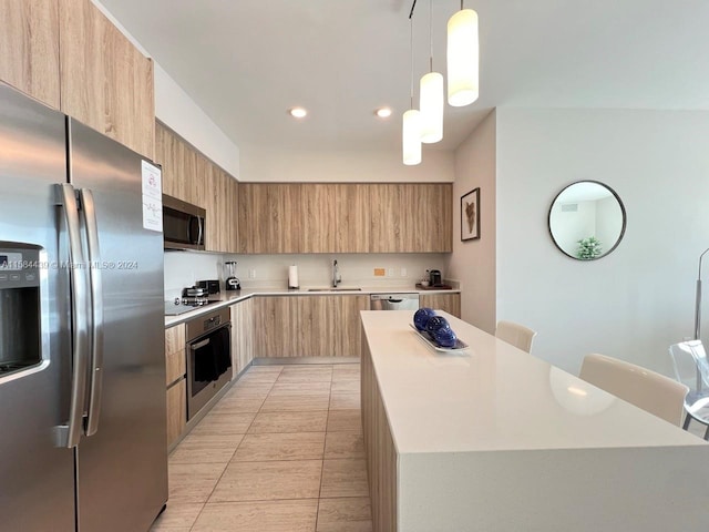 kitchen with decorative light fixtures, stainless steel appliances, light tile floors, sink, and a kitchen island