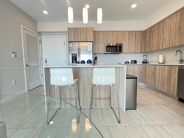 kitchen with appliances with stainless steel finishes, a kitchen island, pendant lighting, and light tile flooring