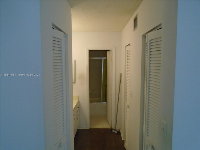 hallway featuring wood-type flooring and a textured ceiling