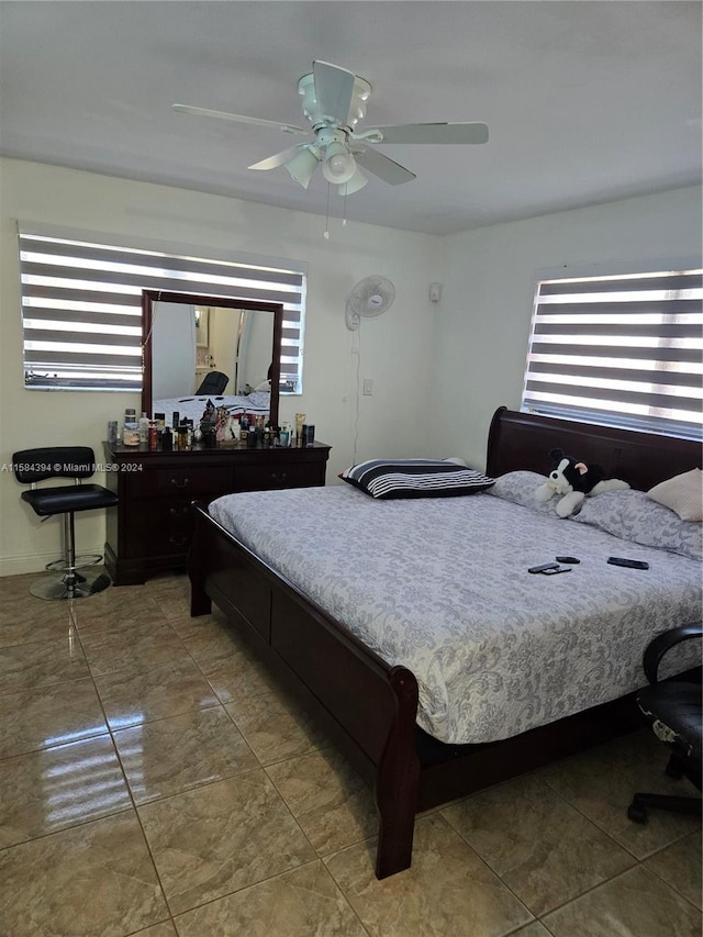 tiled bedroom featuring ceiling fan and multiple windows