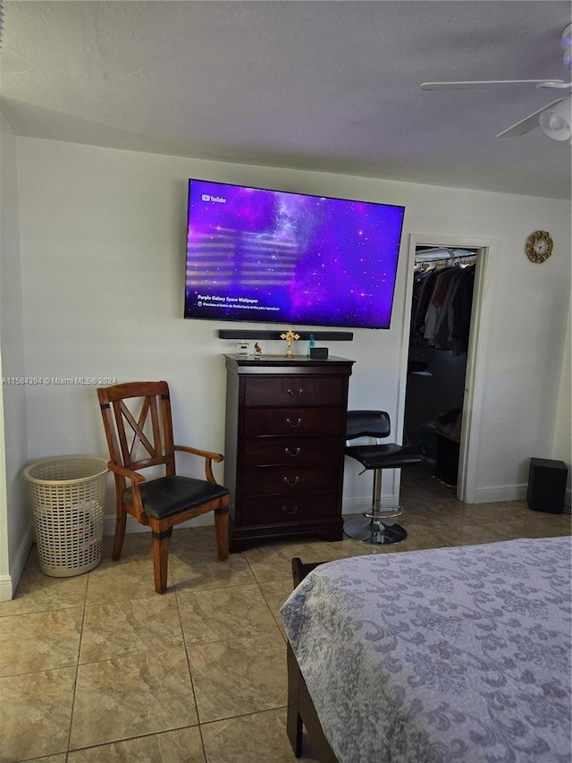 tiled bedroom with ceiling fan and a closet