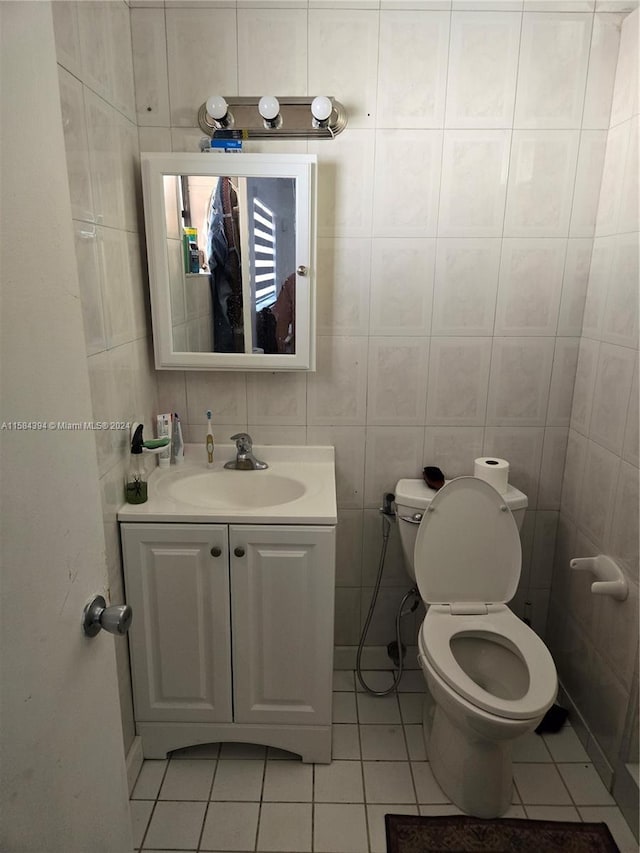 bathroom featuring tile patterned flooring, vanity, toilet, and tile walls